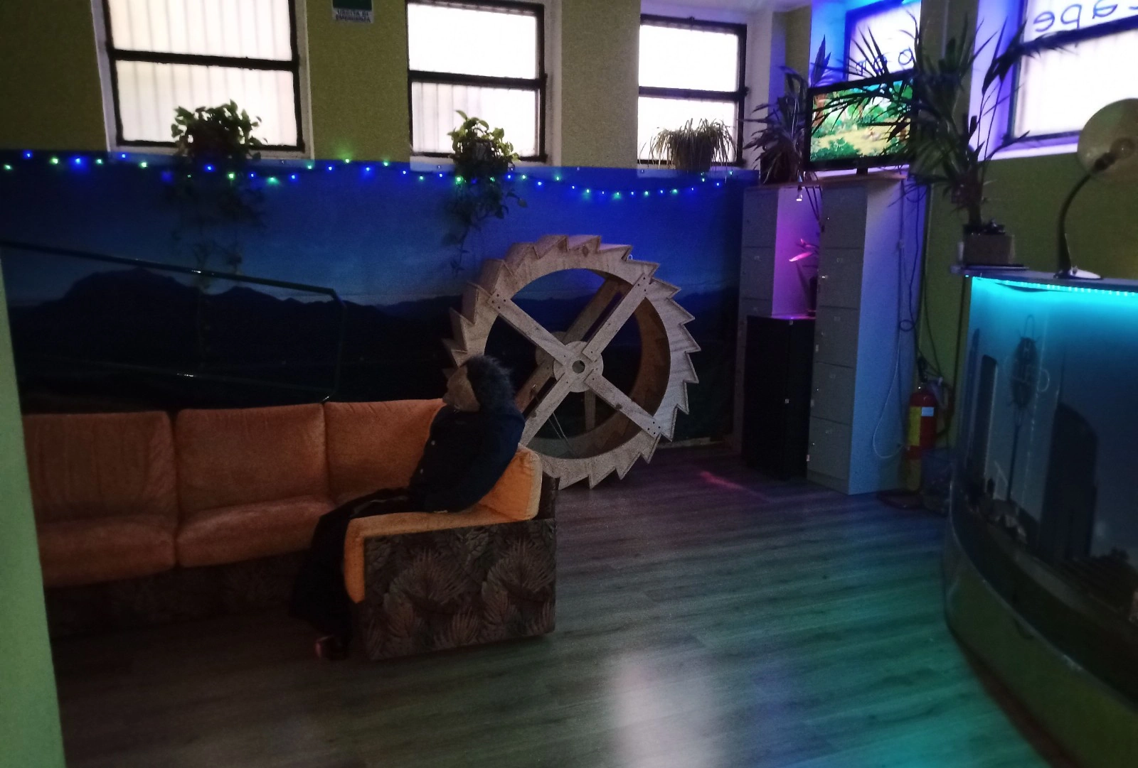 Atrio d'ingresso per team building aziendali a Milano con scenografie mistery, il grande ingranaggio in legno e la mascotte Fritz che accoglie gli ospiti.